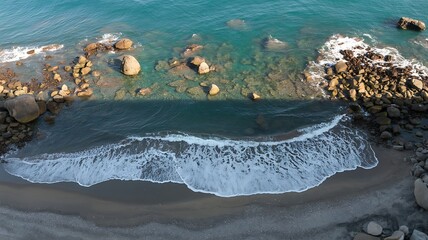 Aerial view of the beautiful turquoise ocean shoreline featuring rocks waves and sandy beach nature scenery