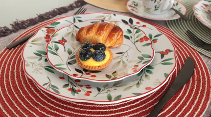 Table setting with bright tableware, berries, and twigs. Dessert on plate. Aesthetics and lifestyle. Home design. 