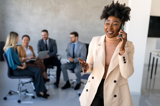 A confident businesswoman leads her busy office life, multitasking with smartphone communication