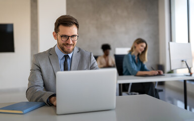 Young businessman using laptop computer in office. Manager thinks about successful financial ideas.