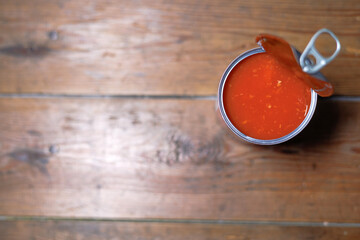 A top view of an opened can of baked beans on a wooden background