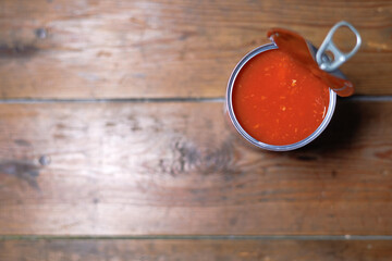 A top view of an opened can of baked beans on a wooden background