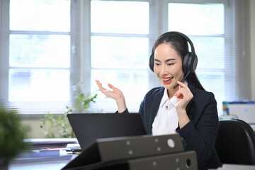 Smiling businesswoman wearing headset talking during online meeting, representing customer service support and communication in modern office