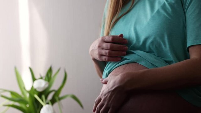 Pregnant woman gently scratching her big naked belly while baby is moving in. 4K