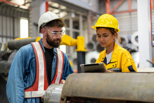 female engineer supervisor advice technician foreman to inspect and check spare part equipment of production machine, team of diverse workers working together at industrial manufacturing factory