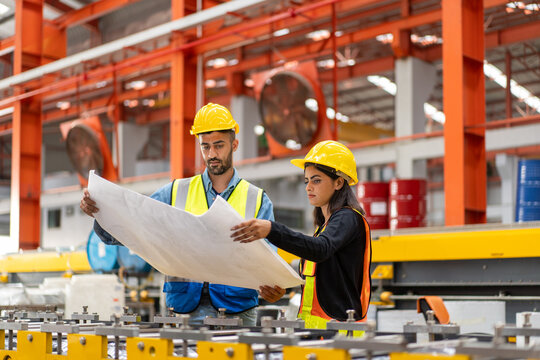 engineer worker man woman in safety vest and helmet check material with blueprint, people working in industrial manufacturing factory planning to inspect repairing equipment in production warehouse