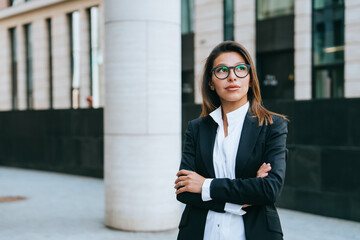 The woman exudes confidence and competence, her business stance accentuated by the urban backdrop, echoing themes of professional success.