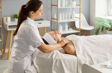 Portrait of a relaxed smiling young pretty woman client lying on couch receiving beauty procedure...