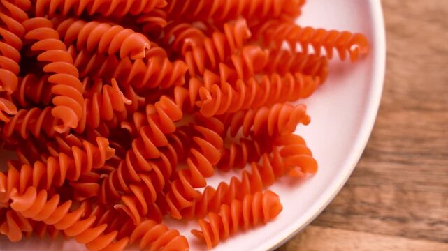 Orange lentil uncooked pasta in ceramic plate on wooden table close up