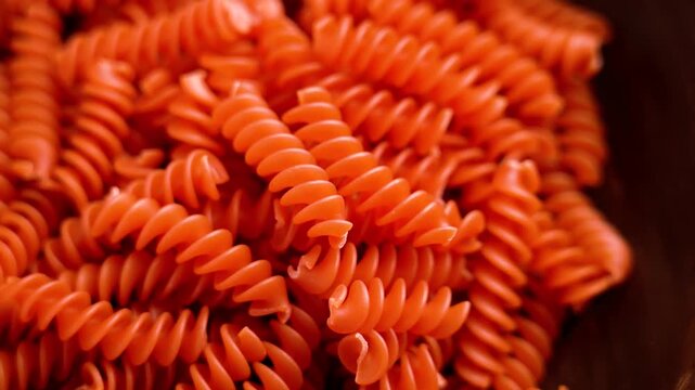 Healthy uncooked gluten free fusilli pasta from red lentils on brown wooden texture