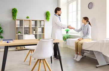 Doctor patient consultation in medical clinic. Man physician greets woman with handshake, starting...