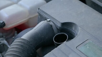 Man opens oil cap on car engine for maintenance inspection in garage. Man removes the oil cap from a car engine to check oil levels