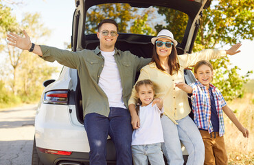 Happy family with children near car trunk. Parents pause on road trip, enjoying travel, weekend...