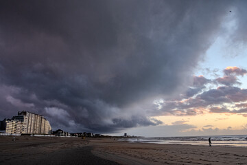 Nieuwpoort, West-Vlaanderen, Belgium, September 13th, 2025, A stunning beach scene with a dramatic sky during sunset, showcasing a lone figure by the tranquil shore