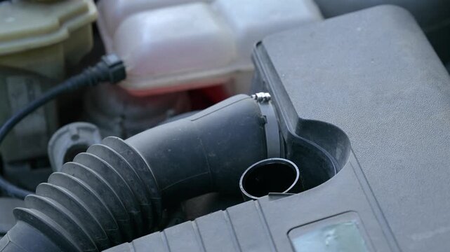 Man adds oil to car engine for routine maintenance at home garage. Man removes oil cap and fills engine with oil to ensure proper functioning and prevent damage