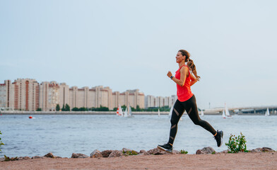 A runner strides energetically along a scenic waterway lined by modern residential buildings, capturing the essence of urban fitness and vitality.