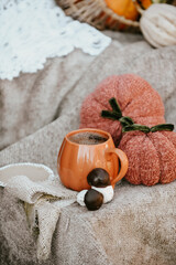 Pumpkin shaped mug of strong black coffee, cozy autumn interior with handmade decorations