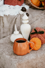 Pumpkin shaped mug of strong black coffee, cozy autumn interior with handmade decorations