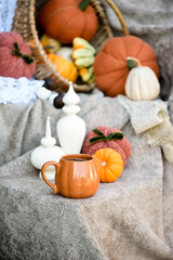 Pumpkin shaped mug of strong black coffee, cozy autumn interior with handmade decorations