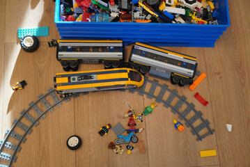 Naklejka premium Toy train set with tracks and colorful toy figures on a wooden floor