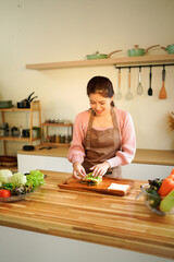 Happy smiling woman in the kitchen preparing a healthy lunch, breakfast, snack with organic ingredients on wooden table.