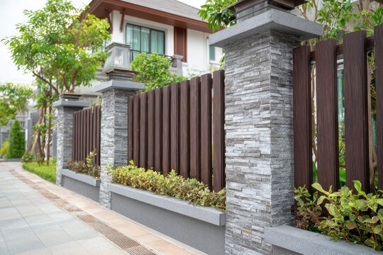 Nice brown wooden fence around house. Garden vinyl fence built with a gray concrete pillar columns surrounding yard. Outdoor landscape. Security and privacy concept. Residential neighborhood.