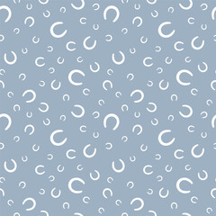 Seamless pattern of white horseshoes in various sizes on soft blue background