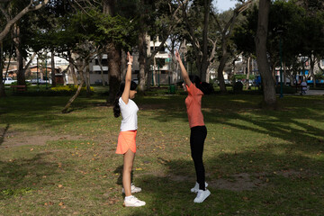 Two teenager are doing yoga in a park