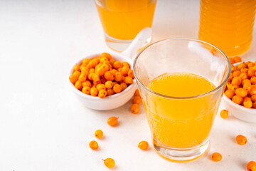 Sea buckthorn (hippophae) juice in jar and glasses on white background copy space