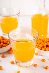 Sea buckthorn (hippophae) juice in jar and glasses on white background copy space