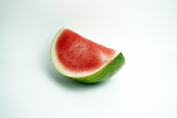 Close-up of a refreshing wedge of ripe red watermelon showing seeds and green rind, isolated on a clean white background, perfect for summer themes.