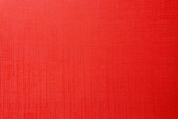 A close-up, top-down view of a bright red textured surface. The minimalist background shows a fine, embossed linen or cross-hatch pattern.
