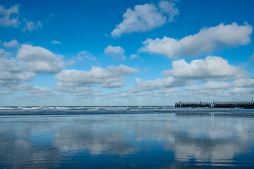 Peaceful surface shows perfect symmetry and calmness, Quiet waters reflect sky and distant pier in balanced harmony