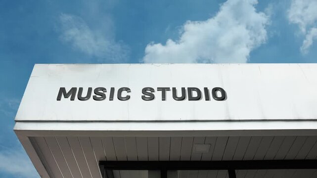A music studio word sign displayed on a commercial production building under a clear blue sky, symbolizing audio recording, sound engineering, and creative production