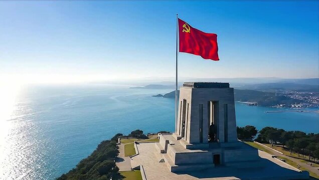 Animated communist flag with hammer and sickle waving over a coastal monument on a sunny day.