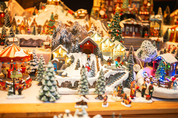 Winter village scene with carousel and small figures engaged in activities