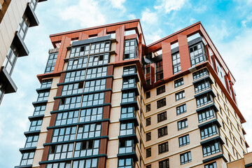 A modern residential building with distinctive angular lines, contrasting facades and windows, viewed from a low angle. New development