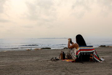 Woman with mobile phone on the beach.