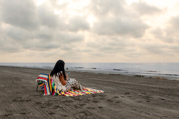 Woman with mobile phone on the beach.