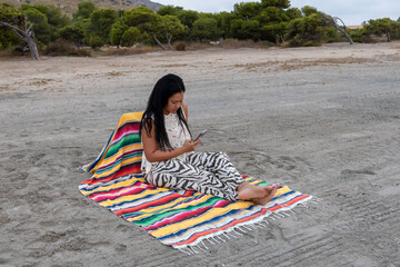 Woman with mobile phone on the beach.