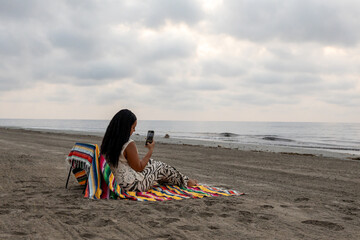 Woman with mobile phone on the beach.