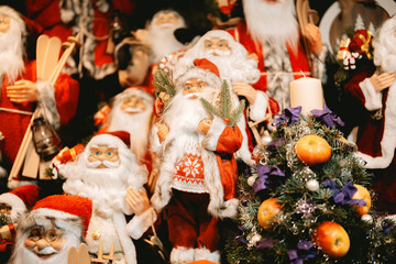 Many santa claus figures standing together in festive holiday decorations with a small decorated tree.