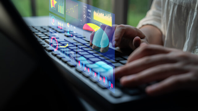 A person interacts with a laptop showcasing holographic financial charts and graphs, emphasizing modern technology and data analysis in a professional workspace. Impute