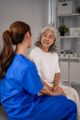 Fototapeta premium Asian Nurse Provides Compassionate Home Care to Smiling Elderly Woman Demonstrating Support and Empathy for Senior Wellness