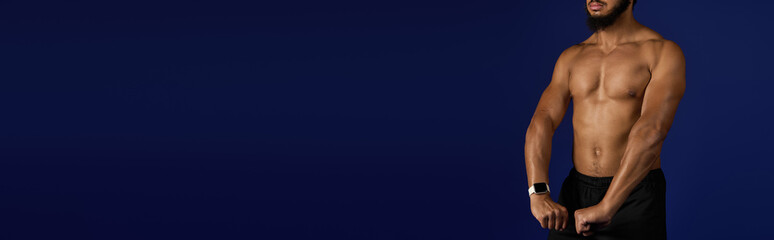 Sportive African American man showcasing strength during workout against blue background