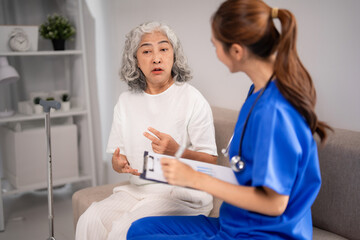 Obraz premium Asian older adult woman patient nurse consultation young caregiver home visit senior health assessment wellness advice professional support medical care discussion