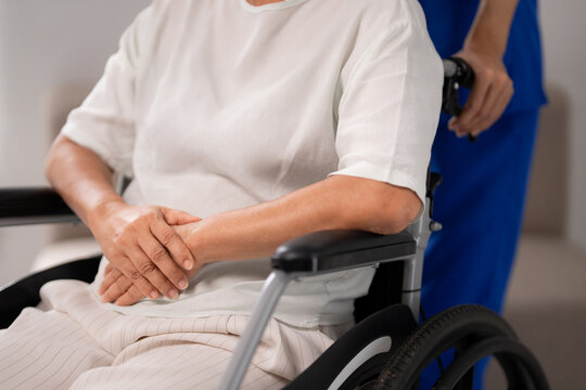 Asian older adult patient receiving professional nursing care assistance in wheelchair by healthcare worker at facility hospital home senior living