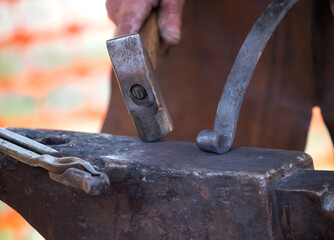 Blacksmith working with glowing coals and metal tools at outdoor forge