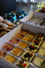 An array of desserts is neatly arranged in clear containers, showcasing vibrant colors and different flavors. The setup is perfect for a festive gathering or celebration.