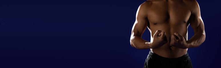Obraz premium Fit African American man demonstrating strength against a vibrant blue backdrop